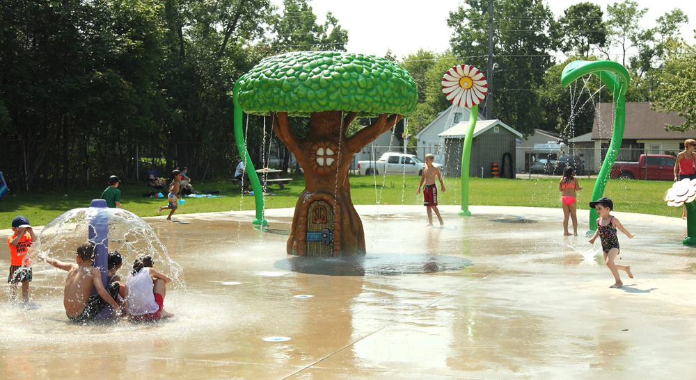 Kids playing at the Parkdale Playground splash pad with nature themes spray features